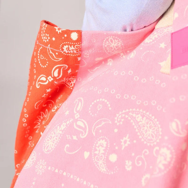 Close-up of a pink fabric with white paisley pattern and an orange fabric with white paisley pattern.