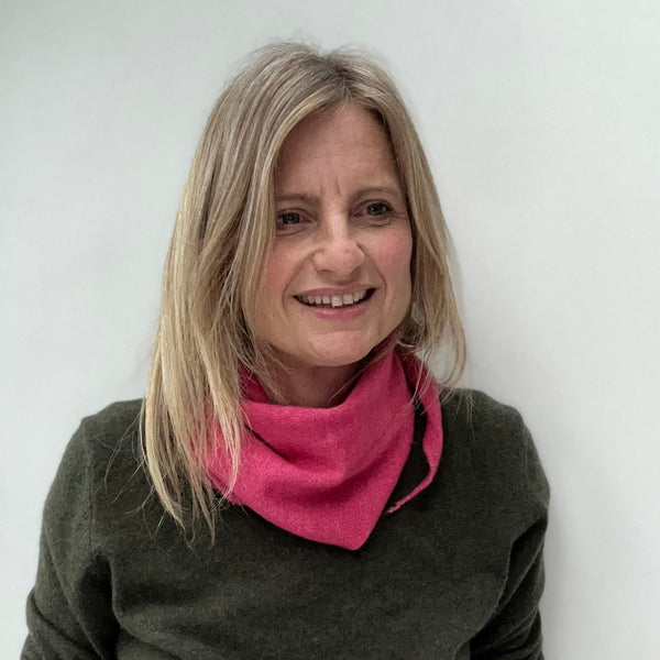 blonde woman with a khaki sweater and bright pink triangle scarf worn as a bandana