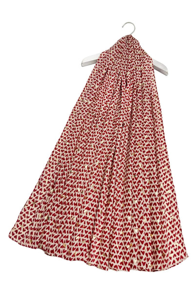 Red and white heart patterned scarf on a hanger against a stone background