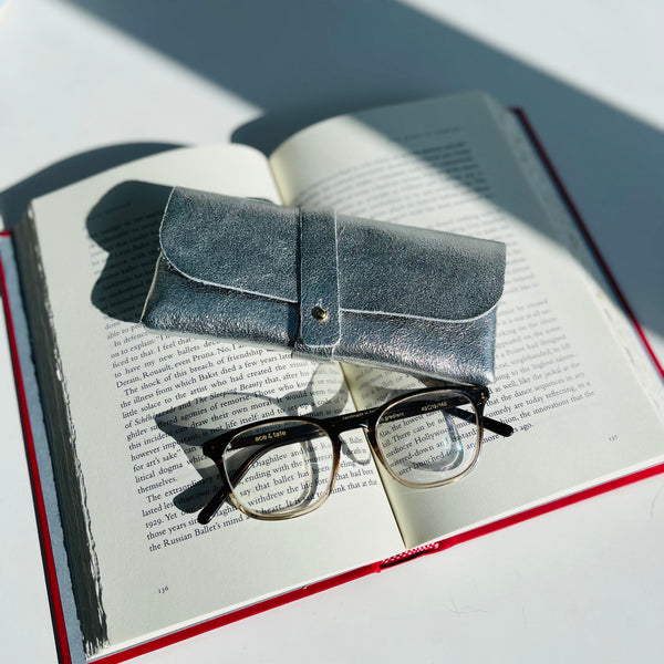 Silver Leather Glasses Case with ace and tate glasses and a book