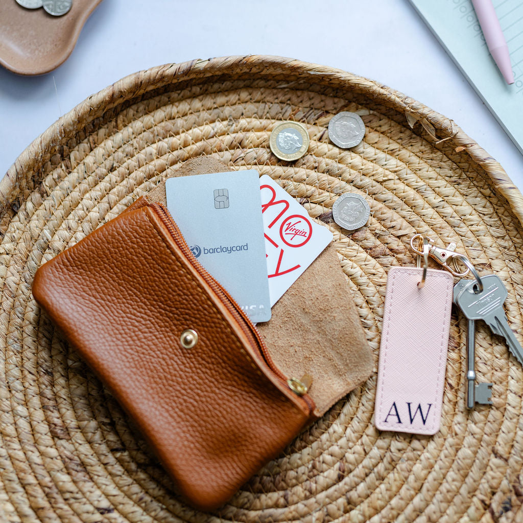 Tan leather wallet with cards and keys on a woven mat