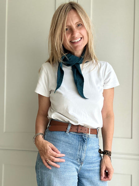 Women in jeans and a white tee shirt wearing a teal wool triangle scarf 