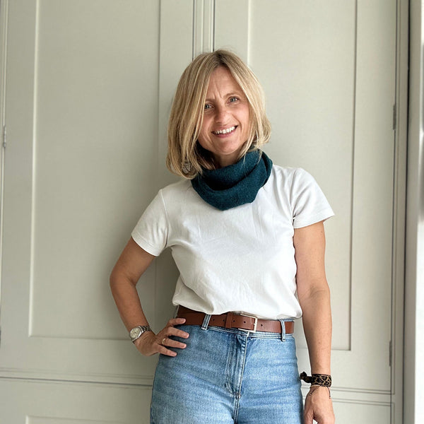 Women in jeans and a white tee shirt wearing a teal wool triangle scarf as a bandana