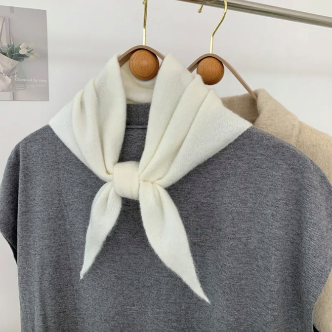 off white triangle skinny knit wool scarf tied over a grey sweater on a wooden hanger