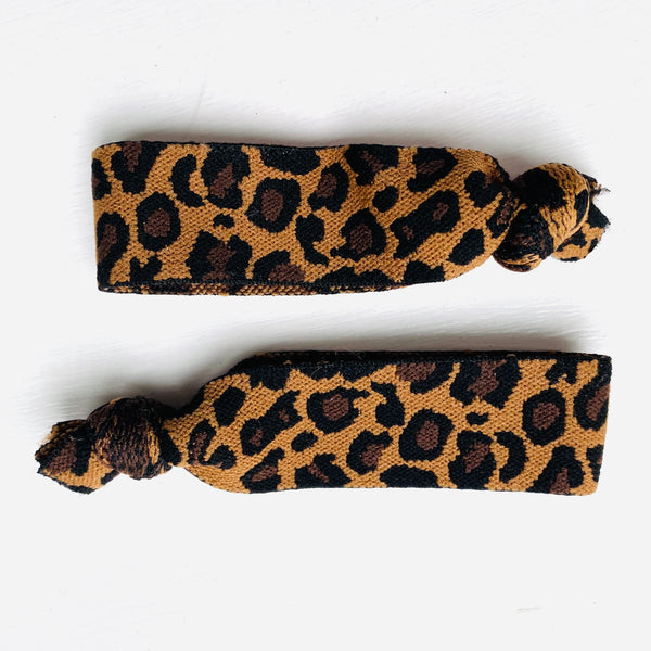 Two leopard print hair elastics tied in a knot on a white background.